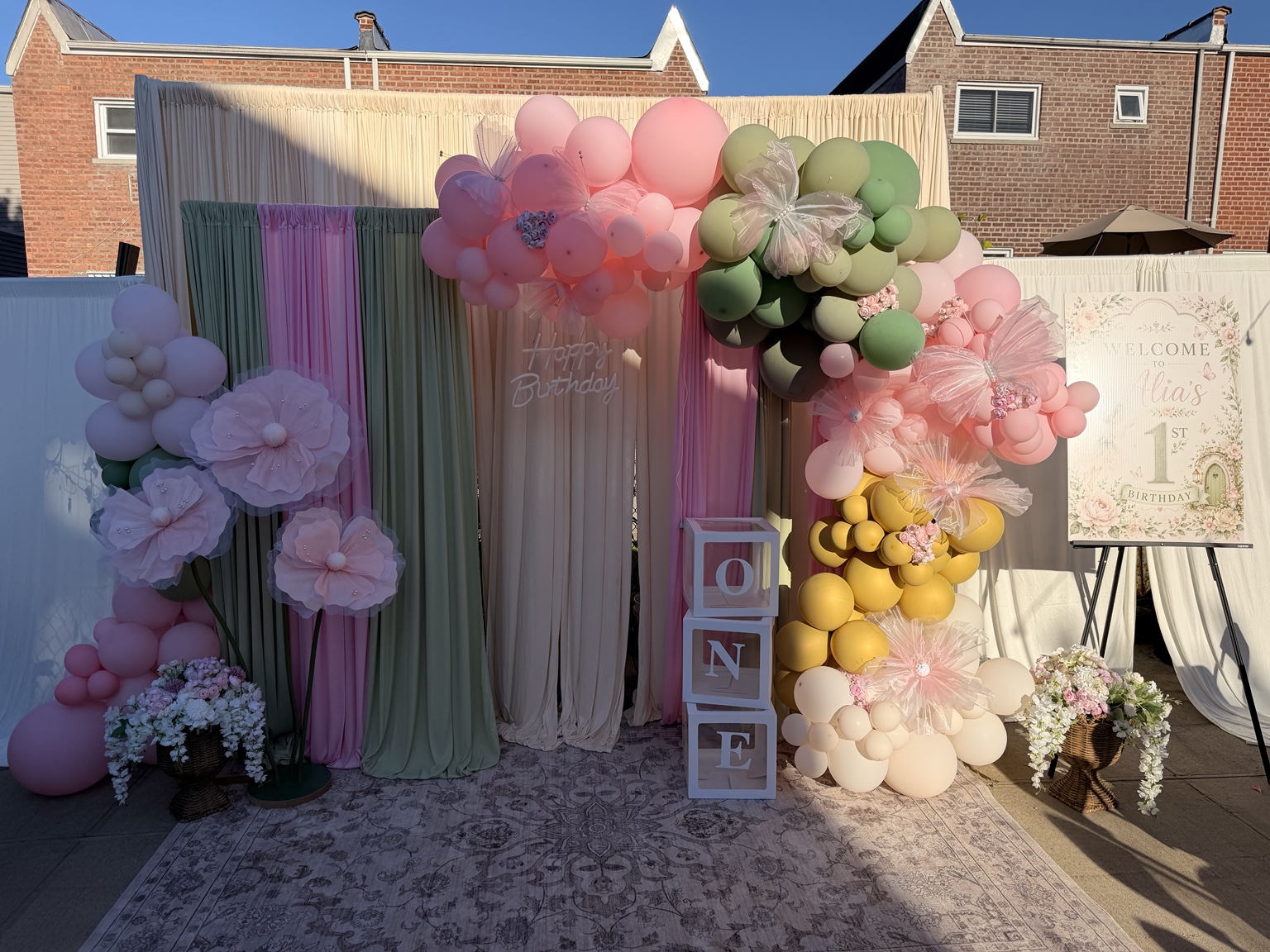Pink, sage and yellow first birthday balloon backdrop with flowers and welcome sign by Arinay Events