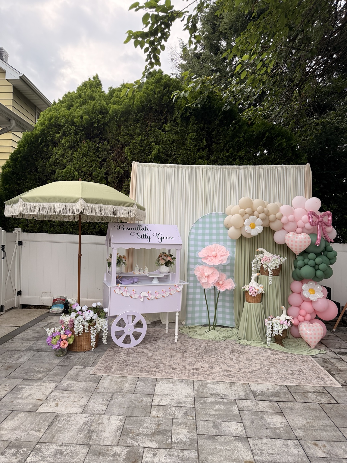 Pastel first birthday décor with balloon arch, florals, cart and draped backdrop by Arinay Events