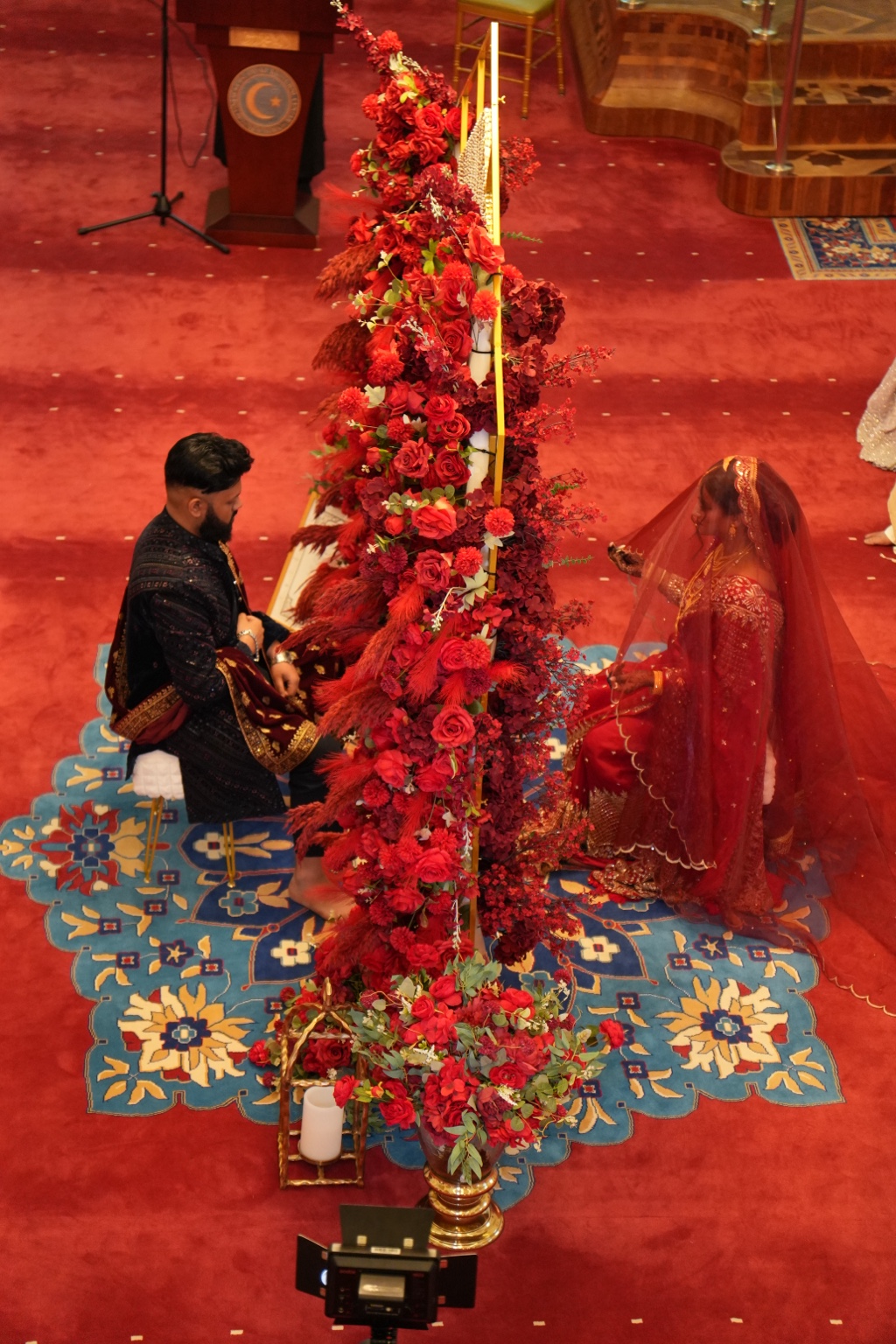 Red floral Nikkah ceremony installation with bride and groom by Arinay Events